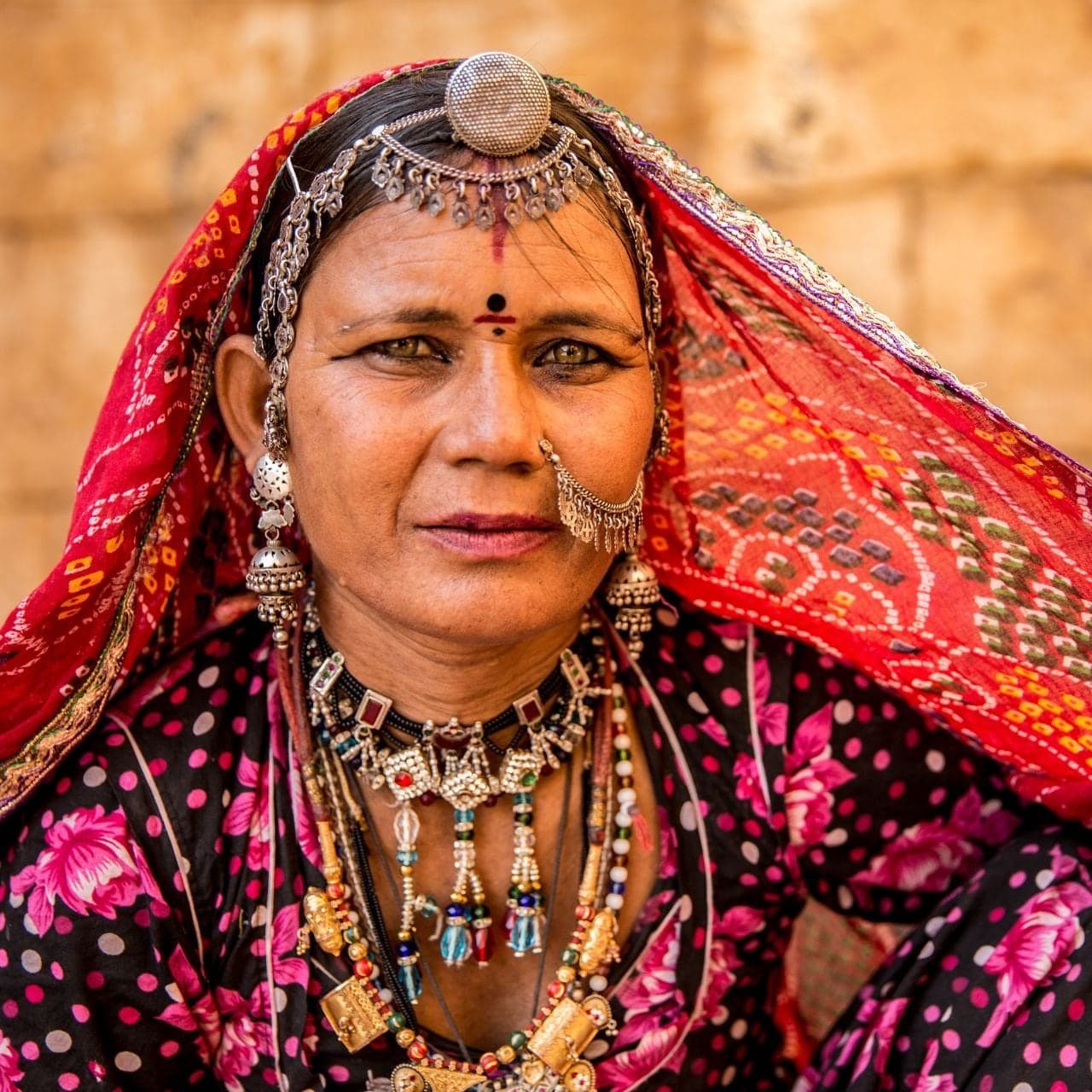 Portrait of a Rajasthani woman in a red veil with traditional silver jewellery