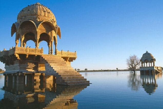 Carved sandstone chhatris standing in the still water of Gadisar Lake in Jaisalmer