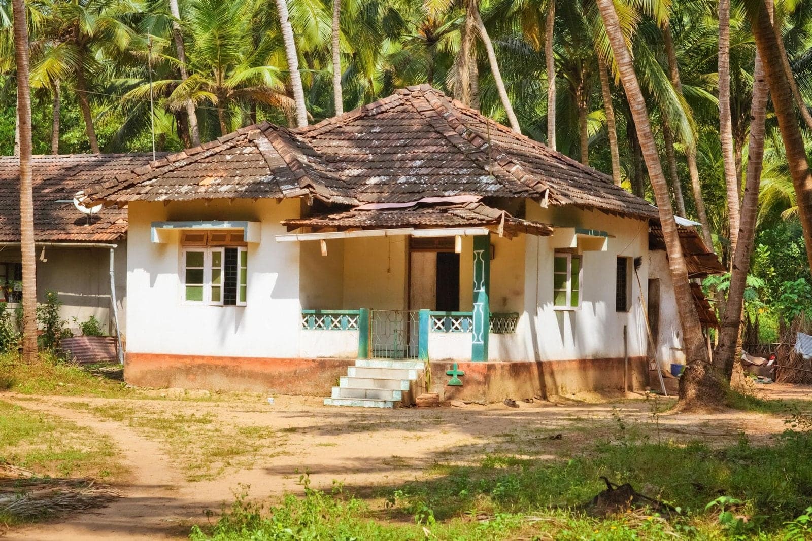 A traditional tiled-roof Goan cottage among coconut palms