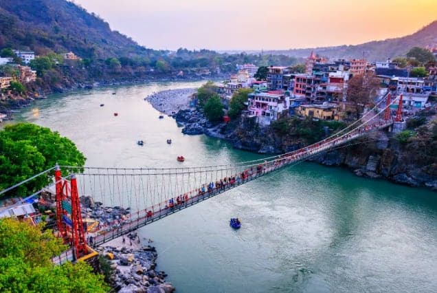 The Lakshman Jhula suspension bridge over the Ganges in Rishikesh, with rafts on the river