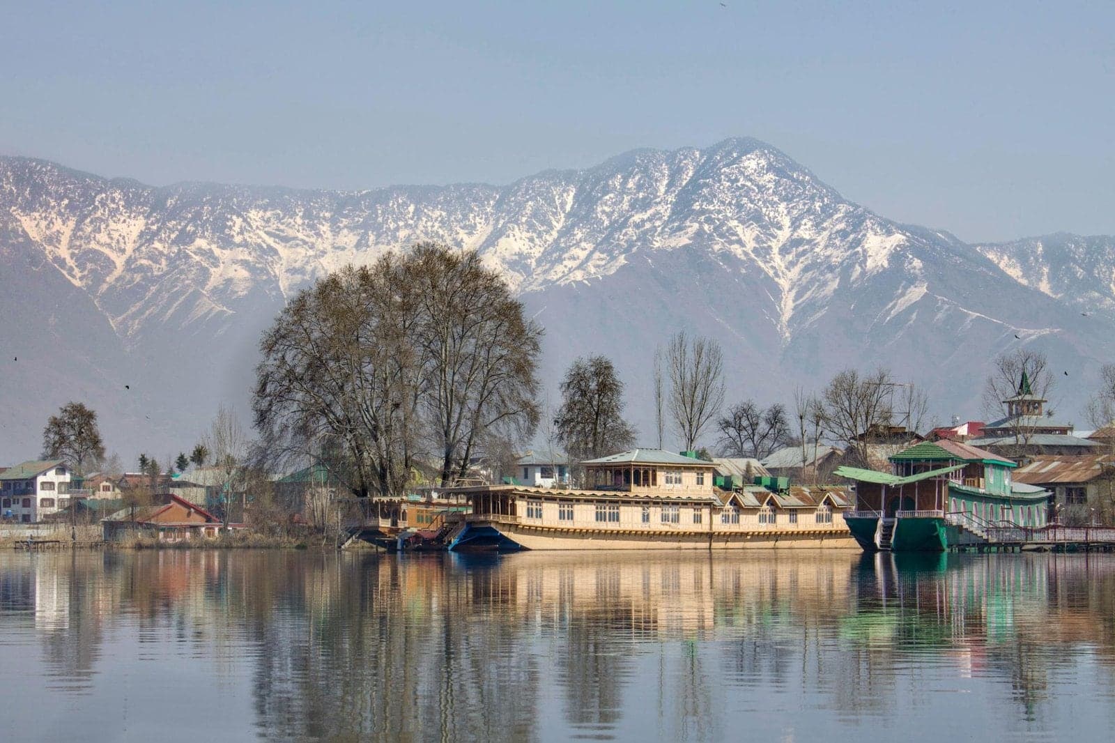 Houseboats on the still water of Dal Lake, below snow-capped mountains