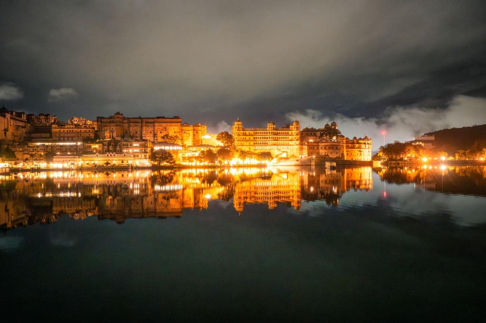 The illuminated City Palace of Udaipur reflected in Lake Pichola at night
